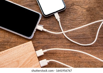 two smart phone charging with power bank on wooden table  - Powered by Shutterstock