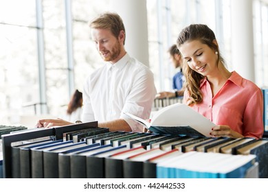 Two  smart students reading and studying in library whole searching through books on the shelves