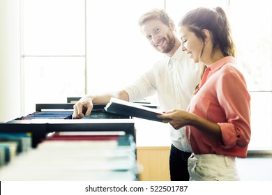 Two  smart students reading and studying in library whole searching through books on the shelves