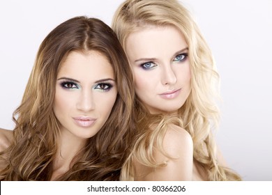Two smiling attractive girl friends - blond and brunette on white background