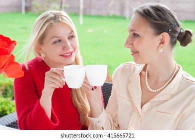 Two Smiling Beautiful Women Having A Cup Of Coffee In Cafe