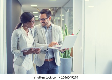 Two Smiling Business People With Laptop Discussing About New Project In Office