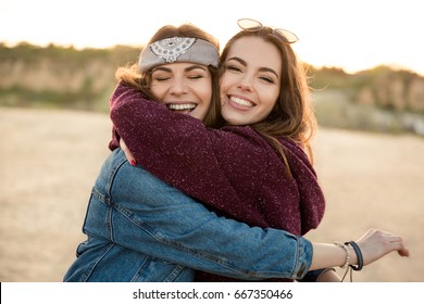 Two Smiling Female Friends Hugging Each Other On The Beach