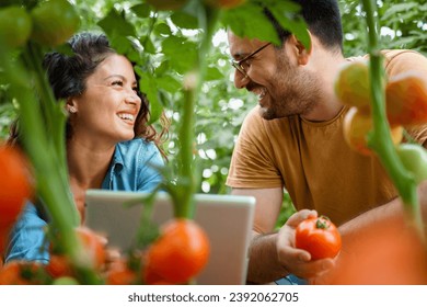 Two smiling happy agronomists looking face to face while conducting quality control in greenhouse. - Powered by Shutterstock