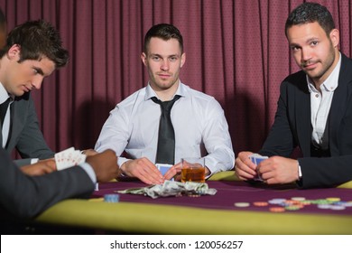 Two smiling men looking up from poker game in casino