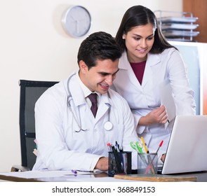 Two Smiling Professional Doctors Brainstorming And Sharing Information In Clinic