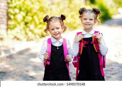 Two Smiling student girl wearing school backpack. Portrait of happy Caucasian young girl outside the primary school. Closeup face of smiling schoolgirl looking at camera.