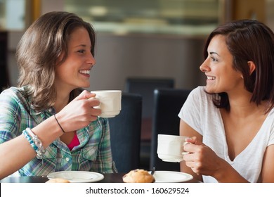 Two smiling students having a cup of coffee in college canteen