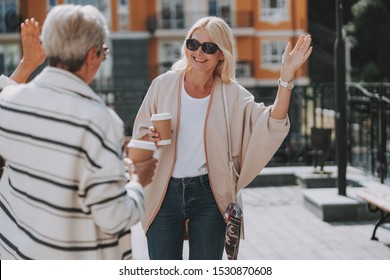 Two Smiling Stylish Ladies Saying Goodbye To Each Other Outdoors