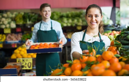 Two smiling supermarket workers in apron arranging citrus in fruit section
 - Powered by Shutterstock