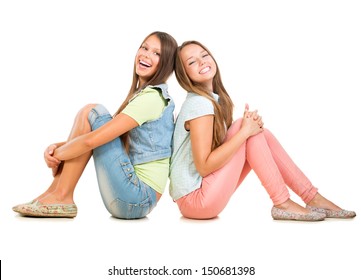 Two Smiling Teenage Girls Friends Isolated On White Background. Teenagers Sitting On A Floor Back To Back And Laughing. Full Length Portrait Of Students. Friendship