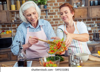 Two Smiling Women Cooking Vegetable Salad Together