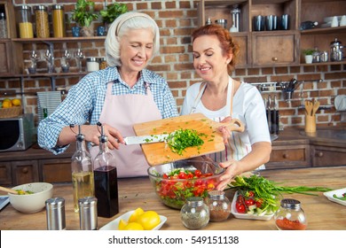 Two Smiling Women Cooking Vegetable Salad Together