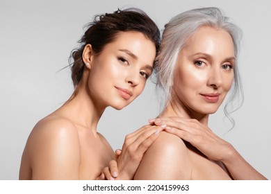 Two smiling women of different ages looking at different side holding hand closeup portrait. Young girl cuddling snuggling mom from back.  Relation between parent and adult kid