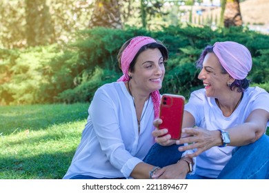 Two Smiling Young Adult Women With A Pink Headscarf Taking A Selfie. 2 Warrior Sisters Laughing And Happy After Overcoming Breast Cancer. Breast Cancer Awareness Day Concept. Image With Copy Space