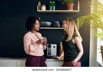 Two Smiling Young Female Work Colleagues Having A Conversation Together While Taking A Break In A Modern Office