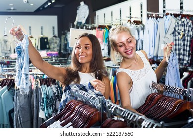 Two Smiling Young Girls Shopping New Pair Of Denim Shorts Together In Clothes Department