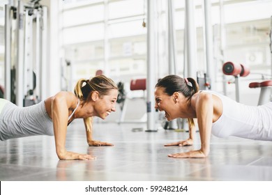 Two Smiling Young Women Exercising In A Gym