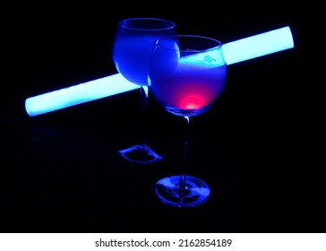 Two Smoky Cocktails With A Neon Tube, On A Dark Background. One Of The Glasses Slowly Igniting Alcohol Inside. Dangerous Liquor Mixture - Close Up Photo. Background Picture.