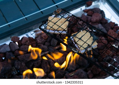 Two Smores Inside A Grill Cooking Over The Fire, A Tasty Canadian Treat With Graham Crackers, Chocolate, And Marshmallow 