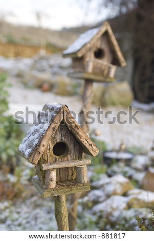 Two snow covered bird boxes, one in focus, one out.