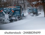 Two snowplows working bakc to back clearing snow and dropping sand at the end of a blizzard in Babylon New York Long Island