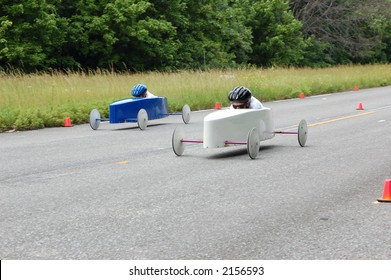 Two Soap Box Derby Drivers Speed Down The Race Track.