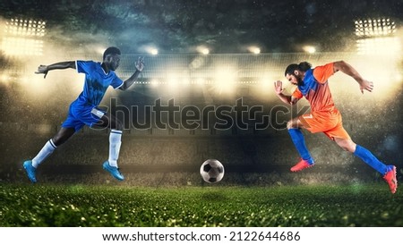 Two soccer players challenge each other chasing the ball at the stadium