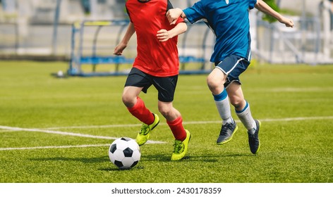 Two soccer players chase a soccer ball in a duel. Boys play soccer match on the grass pitch. Football academy players compete in school tournament. Youth footballers running and kicking ball - Powered by Shutterstock