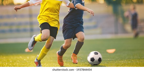 Two Soccer Players in a Duel on Grass Venue. Boys Running After Black and White Soccer Ball. Kids in Soccer Jersey Kits