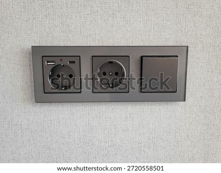 Two sockets and a switch that provide access to electricity on the wall. Electrical sockets for convenient power supply in the office and at home