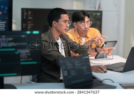 Two software developers collaborate in a modern office while reviewing computer code and building advanced artificial intelligence solutions