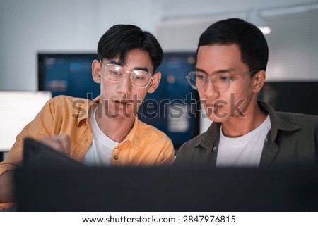 Two software developers collaborate on coding and artificial intelligence research in a modern office workspace