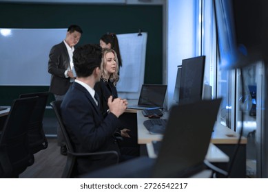 Two software developers engage in pair programming or a code review, discussing a complex function. In the background, team members map out the system architecture on a whiteboard for the next sprint.