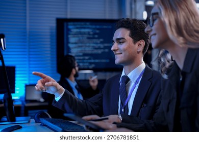 Two software developers smile with satisfaction during a pair programming session, as one points to a successfully executed block of code after solving a complex programming problem.