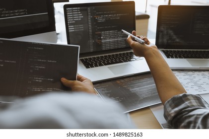 Two software developers are using computers to work together with their partner at the office desk.