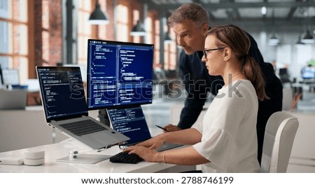 Two Software Engineers Discussing Secure Coding Solutions At Office Desk.