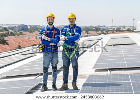 Two solar panel installation workers in hardhats and safety gear standing on a rooftop.