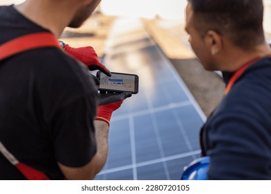 two solar panel technicians are looking on smart phone at electrical insulation.