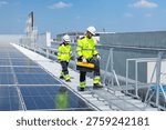 Two solar technicians installing and inspecting photovoltaic panels across a large industrial rooftop solar power system.