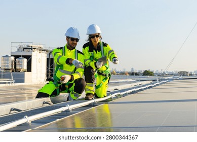 Two solar technicians walking across rooftop photovoltaic panels while inspecting installation and monitoring system performance in evening light.