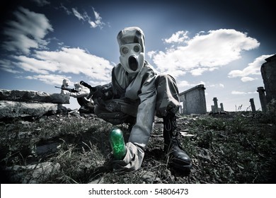 Two Soldiers In The Gas Masks And Protective Clothes Are Testing Biological Weapon On The Ruined Background.