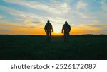 Two soldiers walking across a field at sunset. A dramatic silhouette of two soldiers walking through a field during sunset.