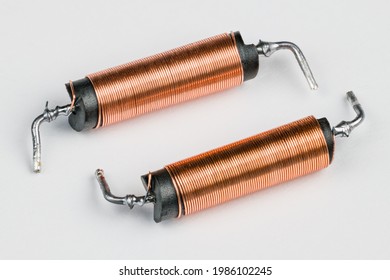 Two solenoids with helical copper wire wound on black coil on white background. Close-up of electronic components with magnetic field inside. Long cylindric inductors with ferrite core. Electromagnet.
