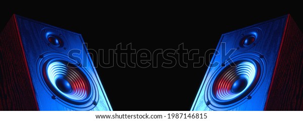 Two sound speakers in neon light with free space\
between them on black.
