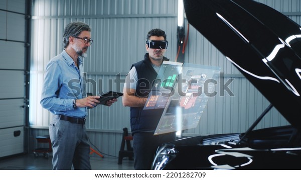 Two specialists carry out car diagnostics using\
modern tools. They study the indicators and graphs on the screen,\
displaying the condition of the car. Carrying out repairs in a\
technological workshop.