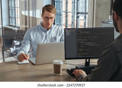 Two IT specialists co-working at office, working on new product, analyzing data, programming new software