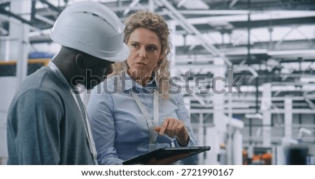 Two Specialists Solve Technical Issue in Vast Industrial Plant. Woman Points Area Concern on Factory Floor, Using Tablet For Data Reference. Problem Solving and Operational Excellence in Industry 4.0.