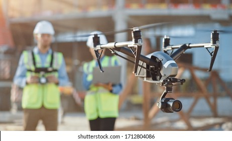 Two Specialists Use Drone on Construction Site. Architectural Engineer and Safety Engineering Inspector Fly Drone on Building Construction Site Controlling Quality. Focus on Drone - Shutterstock ID 1712804086