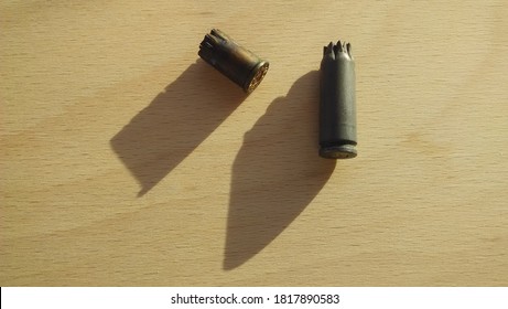 Two Spent Bullet Casings On A Wooden Surface